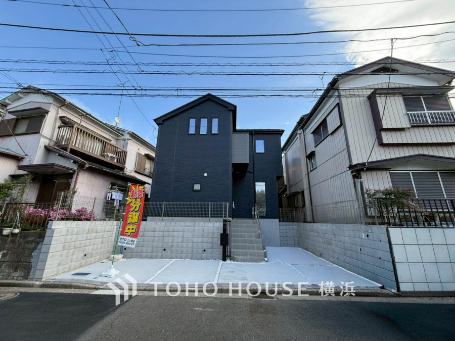 閑静な住宅街に新築分譲のモダンな外観。広々とした駐車スペースと通りより一段高い位置でプライバシーが保たれる邸宅です。