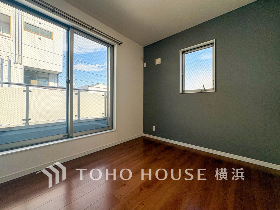 大きな窓から自然光が差し込む、落ち着いた色合いのシンプルな洋室。快適な居住空間を実現します。