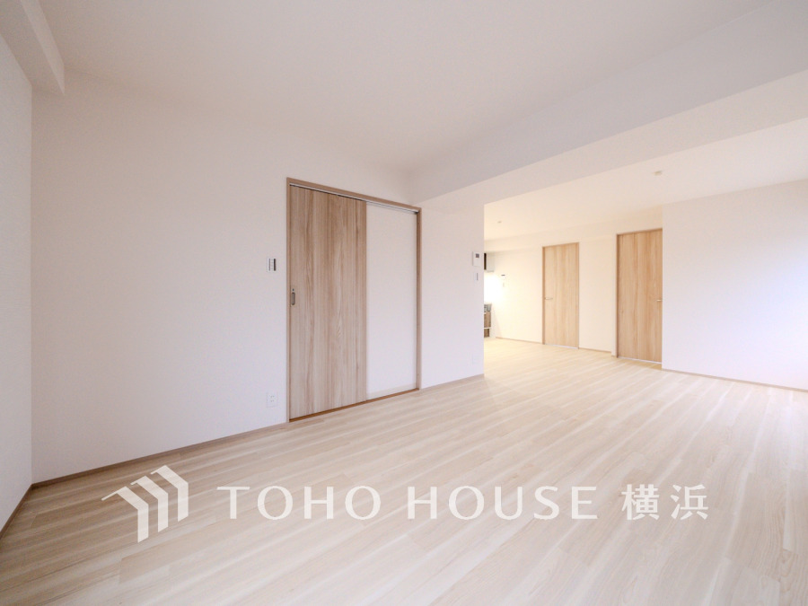 明るく広々としたリビングは、ナチュラルな木目調の床と白い壁で落ち着いた空間を演出しています。