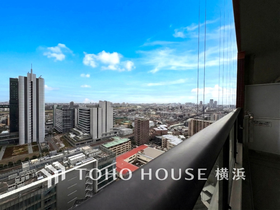 高層階から望む開放的な眺望。都市の景色と青空が広がる、心地よいバルコニー空間です。