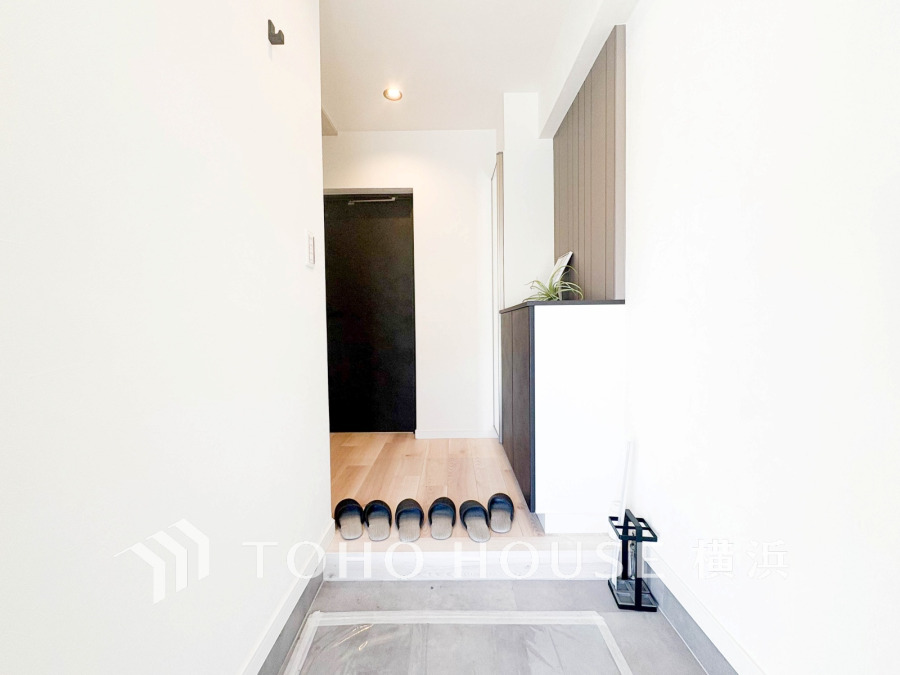 シンプルで清潔感あふれる玄関スペース。収納棚とスリッパが整然と並び、快適な住まいの第一印象を演出します。