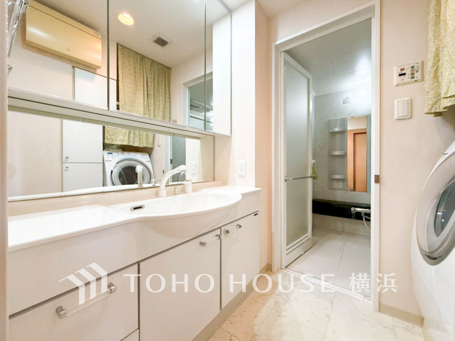 清潔感あふれる洗面スペース。大きな鏡と収納で使いやすく、隣接の浴室と洗濯機で家事動線もスムーズです。