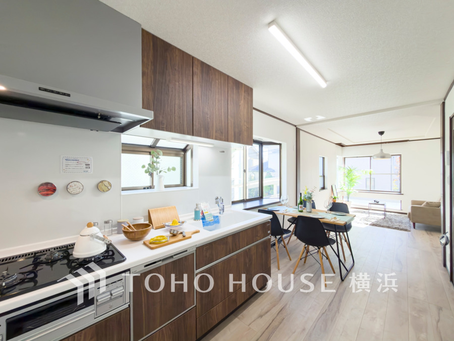 木目調のキッチンと明るいダイニングが調和した、開放感あふれるリビング空間です。自然光が心地よく差し込みます。