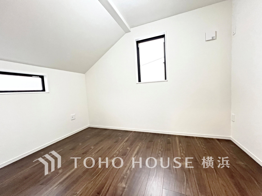 明るい二面採光、勾配天井が特徴の洋室。シンプルな内装で多目的に活用可能です。