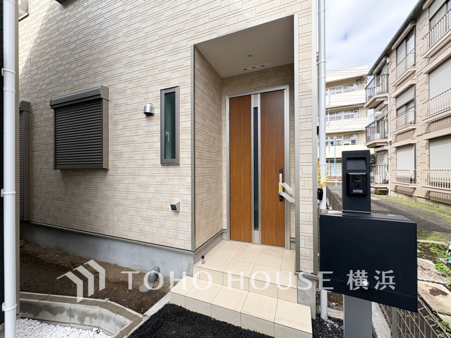 スタイリッシュな木目調ドアと防犯カメラ付きインターホンを備えた、安心・快適な玄関スペースです。