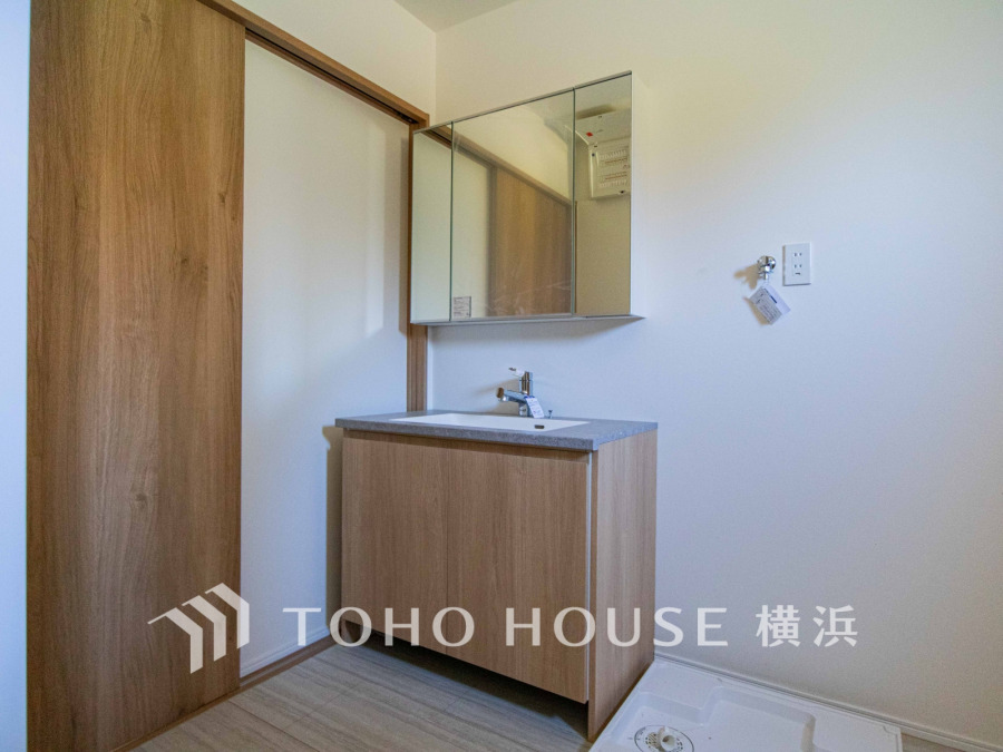 木目調の洗面台と収納が落ち着く、シンプルで機能的な洗面スペースです。清潔感あふれる空間設計。