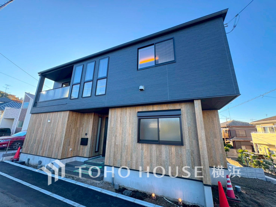 モダンな木目とブラックの外壁が調和するデザイン住宅。開放的な窓で自然光をたっぷり取り込めます。