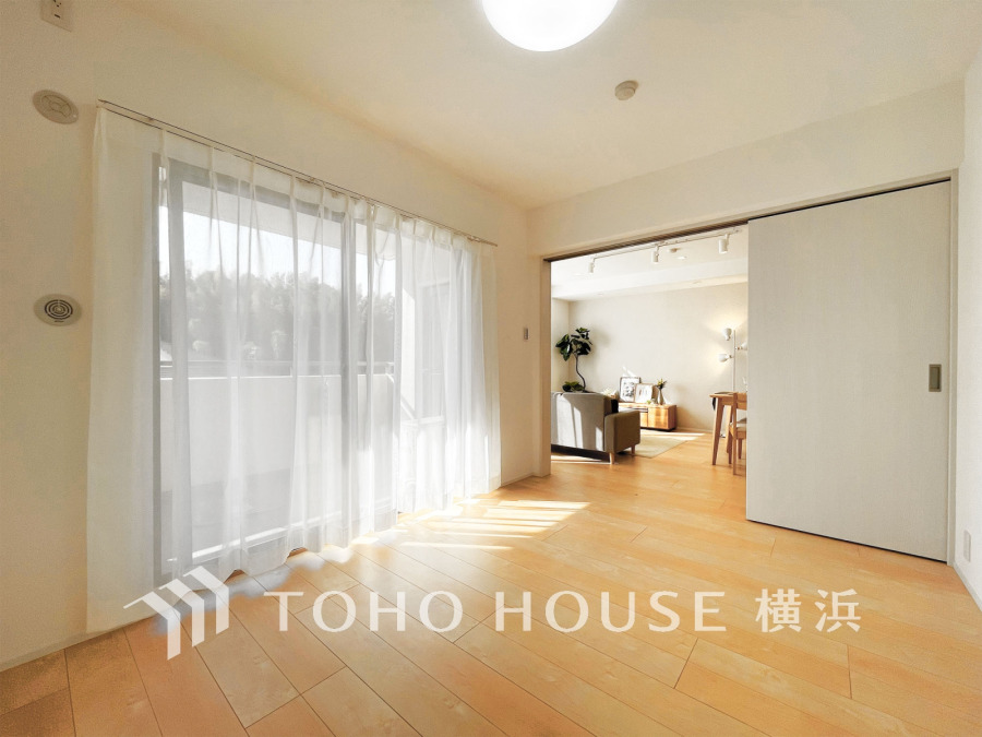 バルコニーから陽射しが差し込む洋室。リビングと繋がる開放感が魅力の快適な空間です。