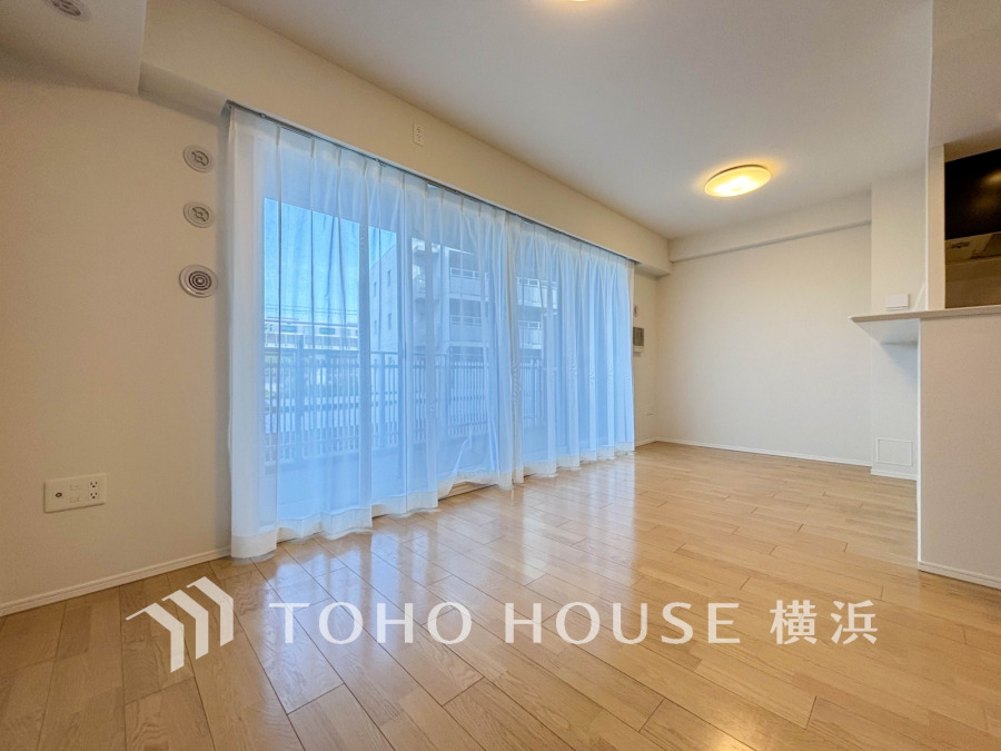 大きな窓から自然光が注ぐ明るいリビング。ナチュラルなフローリングが温かみを演出します。