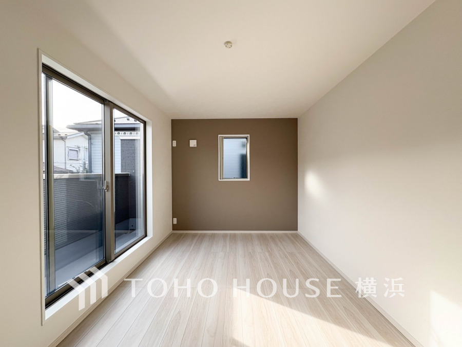 ナチュラルな色合いで統一された明るい洋室。大きな窓から光が差し込み、開放感あふれる空間です。