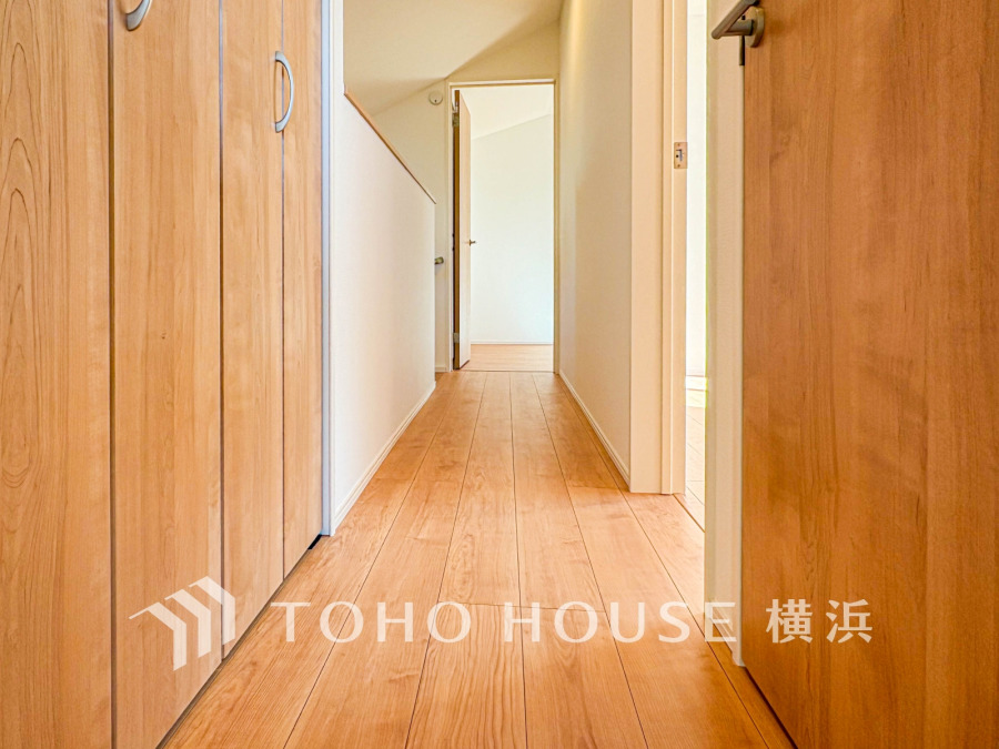 温かみのある木目調のフローリングと収納扉が調和した、明るく清潔感あふれる廊下空間です。