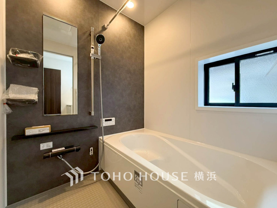 シックなアクセント壁が映える清潔感のある浴室。窓付きで換気も良好な快適空間です。