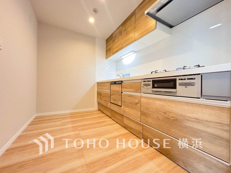 木目調の温かみあるシステムキッチン。広々とした空間で使い勝手も良く、収納も充実しています。