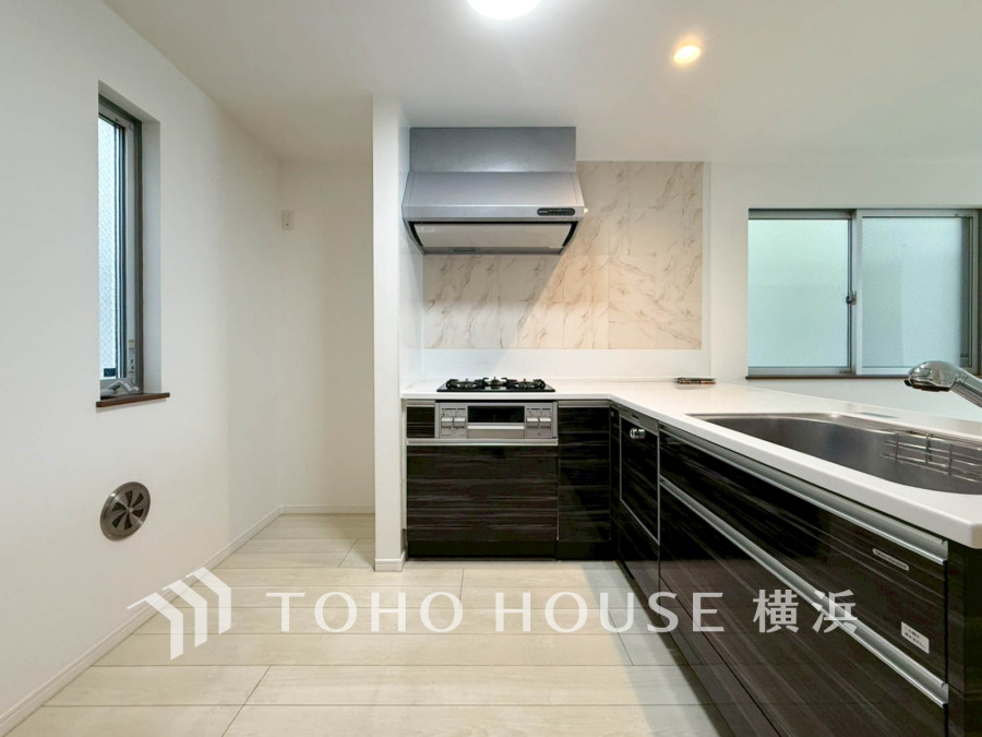 シックなブラックのシステムキッチンは収納豊富で使いやすく、明るい窓から自然光が差し込む快適な空間です。