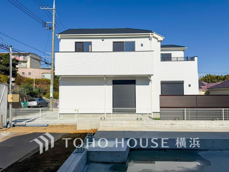 清潔感あふれる白い外観が魅力の新築一戸建て。広い駐車スペースと日当たり良好な立地が特徴です。