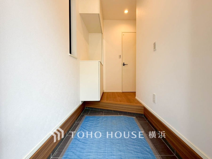 清潔感あふれる白壁と木目調のアクセントが調和した、広々とした玄関スペース。収納も充実しています。