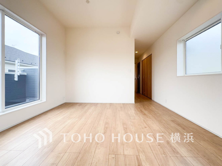 明るい光が差し込むシンプルな洋室。木目調の床が温かみを演出し、快適な居住空間を実現しています。