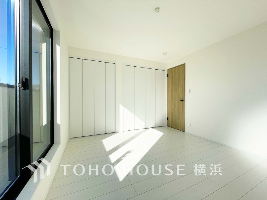 大きな窓から自然光が差し込む、白を基調とした明るく清潔感あふれる洋室です。収納も充実しています。