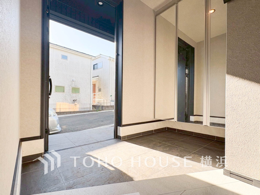 大きな鏡と明るい光が差し込む広々とした玄関スペースで、開放感と使いやすさを両立しています。