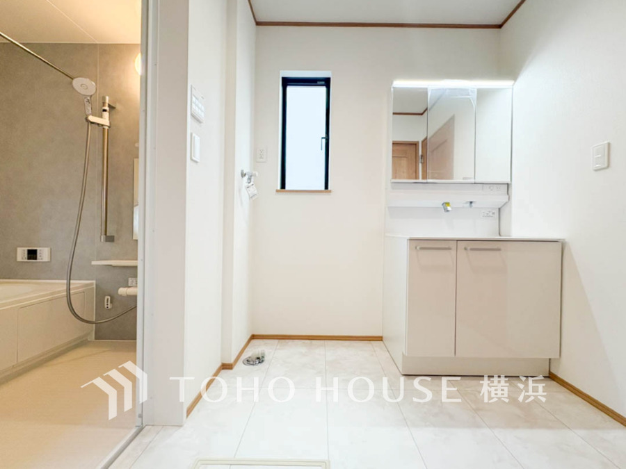 清潔感あふれる洗面所とバスルーム。明るい窓から自然光が入り、快適な水回り空間を演出します。