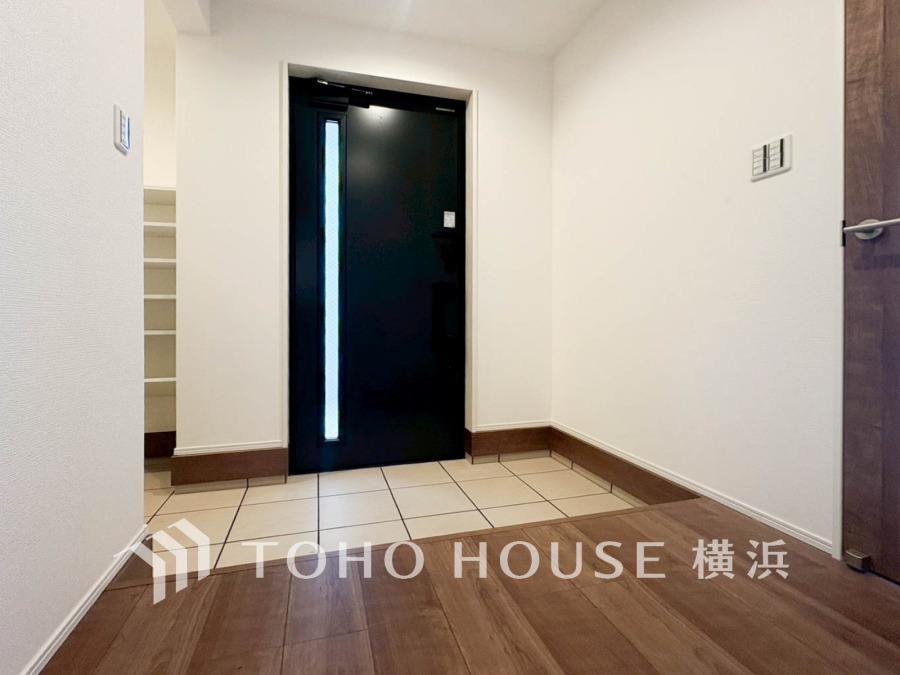 明るく清潔感のある玄関スペース。シンプルなデザインで使いやすく、収納スペースも確保されています。