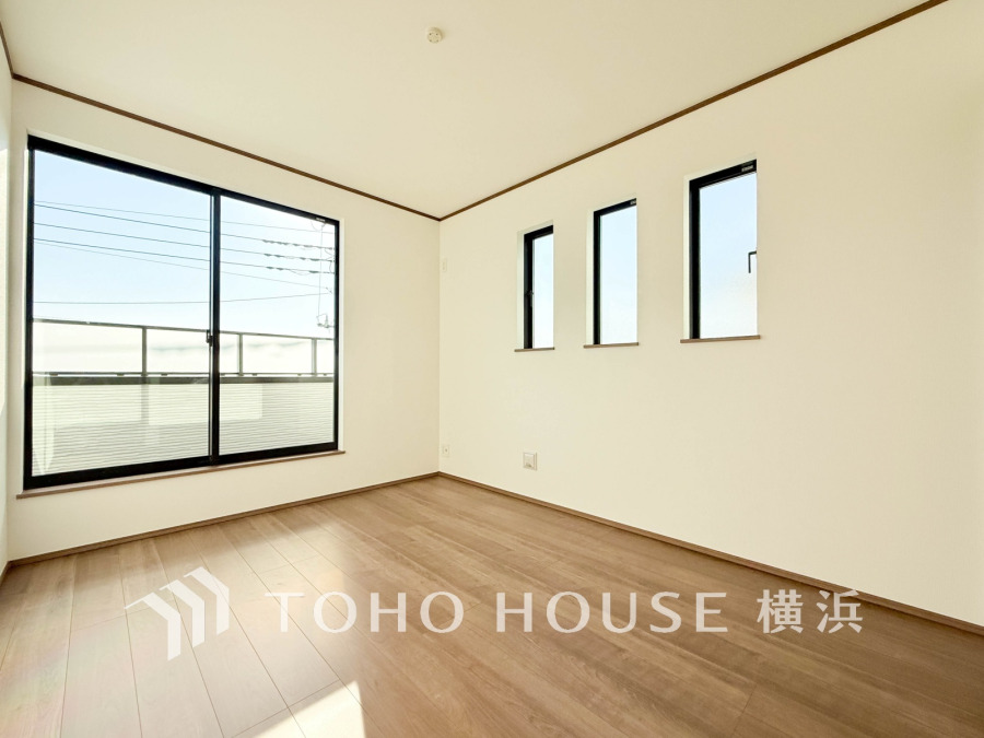 大きな窓から自然光が差し込む明るい洋室。木目調の床が温かみを演出し、快適な居住空間を実現します。