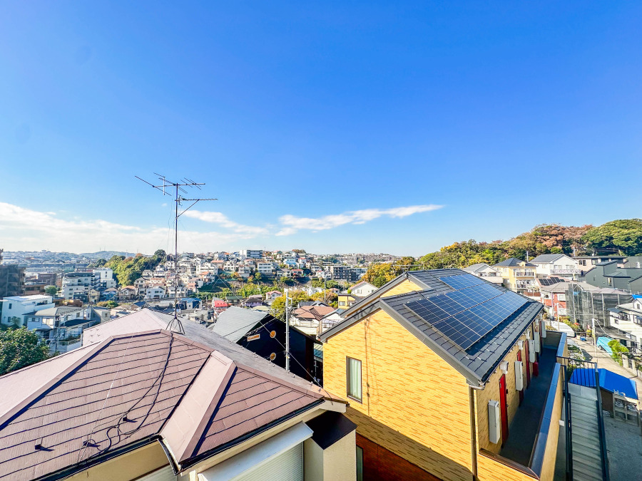 晴天のもと、太陽光パネル搭載の住宅が並ぶ閑静な住宅街。開放的な眺望と豊かな緑が魅力です。