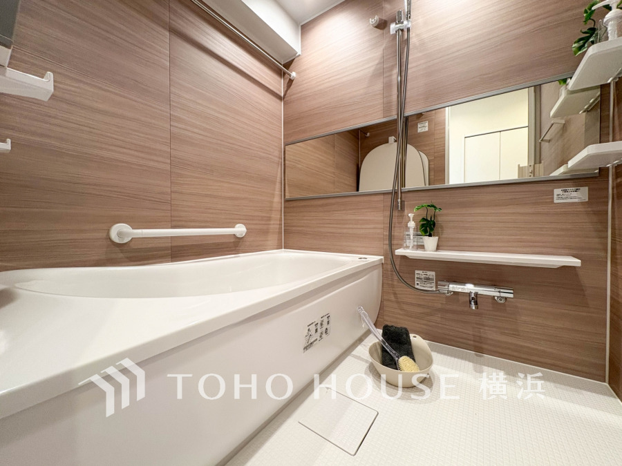 木目調の壁が温かみを演出する、清潔感あふれるバスルーム。ゆったりとした浴槽でリラックスできます。
