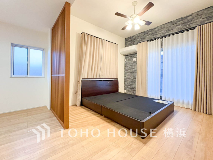 木目調の間仕切りで空間を分けた、落ち着いた雰囲気の寝室。自然光が優しく差し込みます。