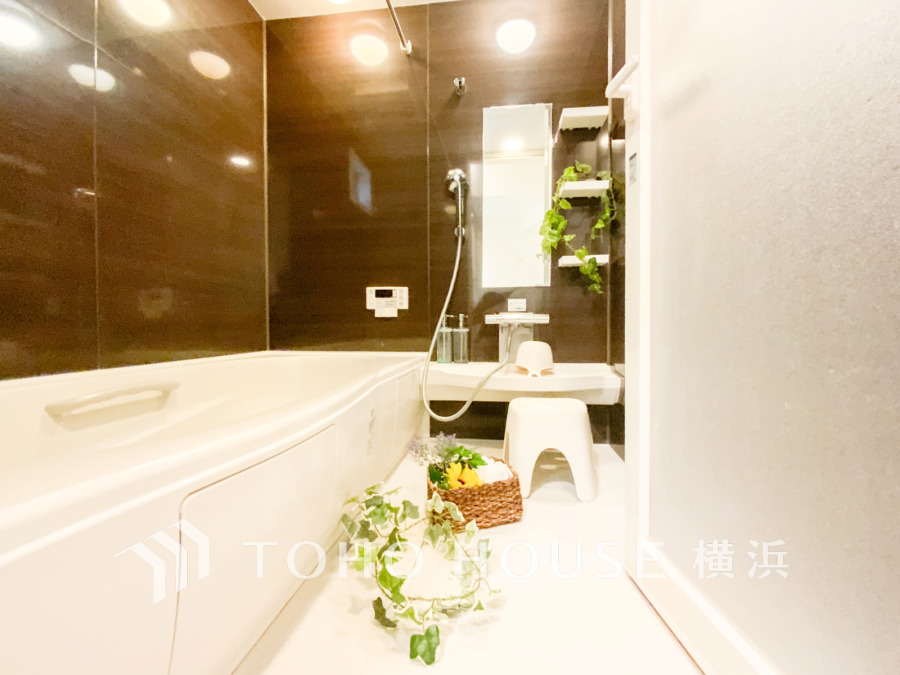 高級感のあるダークブラウンの壁面と白の浴槽が調和した、清潔感あふれる快適なバスルーム空間です。