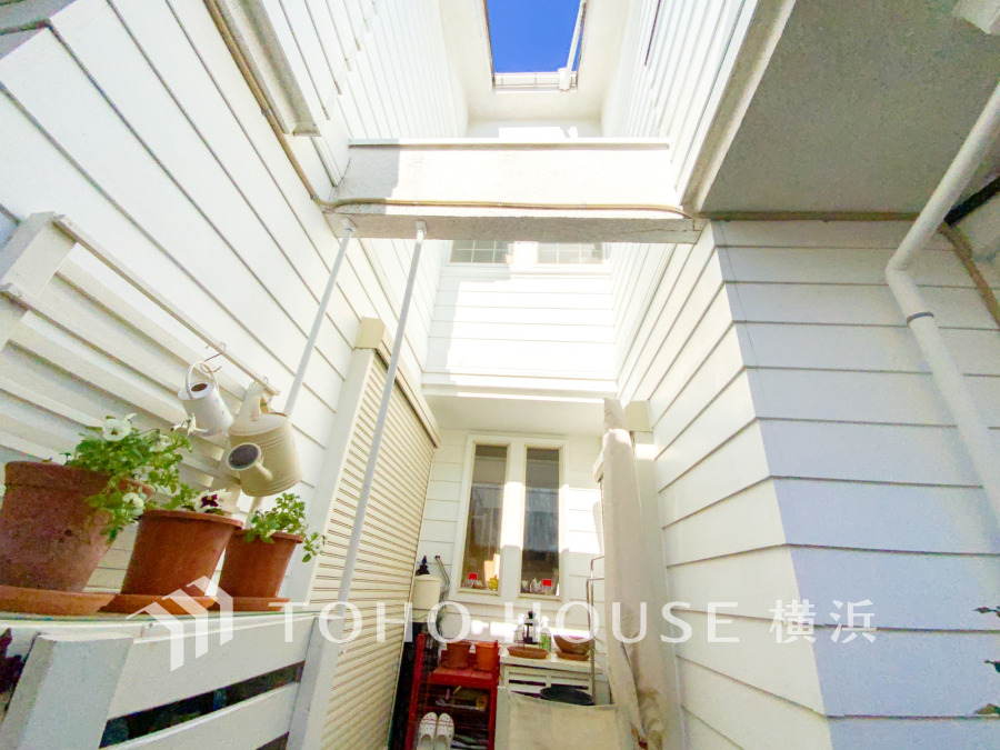 明るい光が差し込む中庭スペース。ホワイトの外壁と植物が調和した、開放感あふれる住まいの一角です。