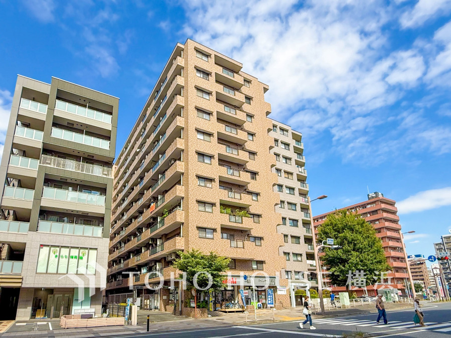 青空の下に佇む分譲マンション外観。整ったタイル張りとバルコニーが並び、街並みに調和する住まいです。