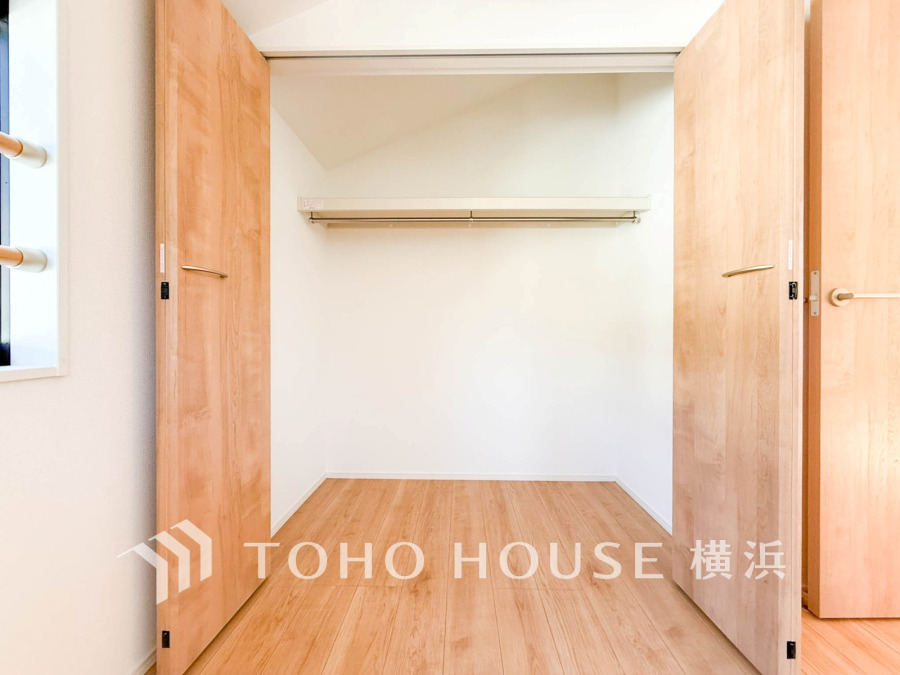 ナチュラルな木目調の扉と床が調和する、大容量で使いやすいクローゼット空間です。明るく清潔感があります。