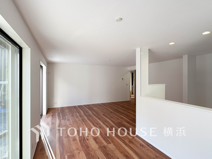 大きな窓から自然光が差し込む、広々とした明るいリビング空間です。木目調フローリングで温かみも感じられます。