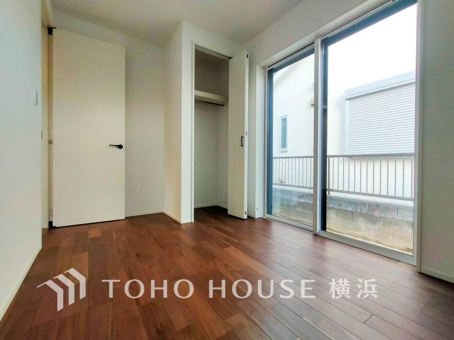 大きな窓から自然光が注ぐ明るい洋室。収納スペースも備え、快適な住空間を実現します。