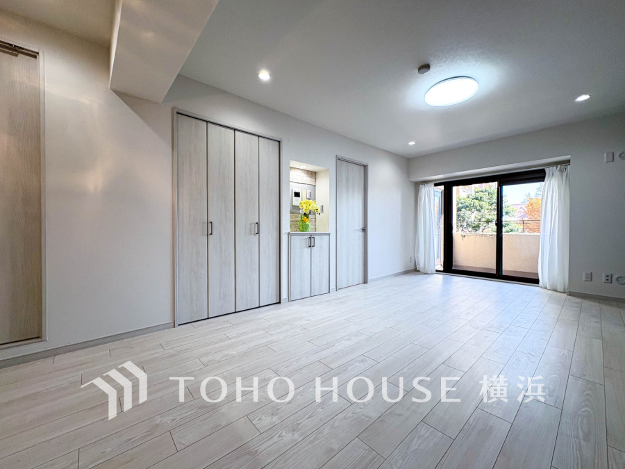 自然光が差し込む広々としたリビング。明るい木目調の床と収納スペースが居心地の良さを演出します。