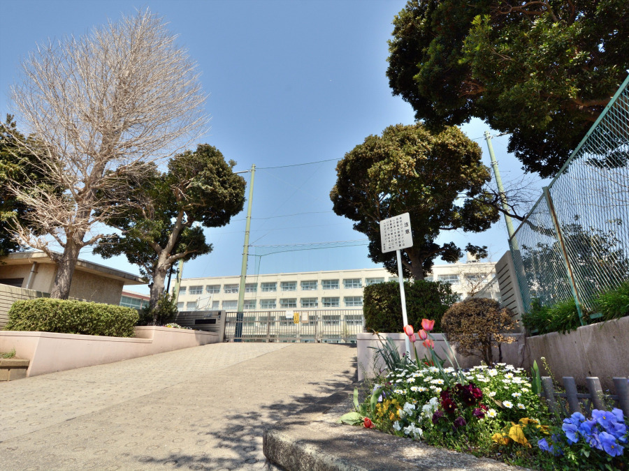 四季の彩りを感じる花壇と緑に囲まれた、安心感あふれる学校の正門入口です。