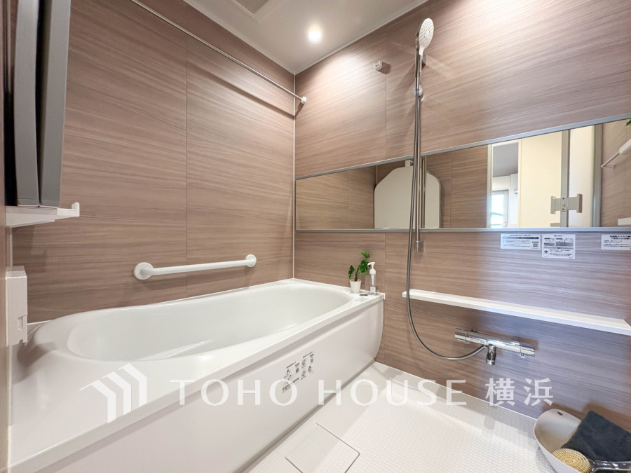 木目調パネルで温かみのある浴室。広い鏡と手すり付きで快適かつ安心してくつろげる空間です。