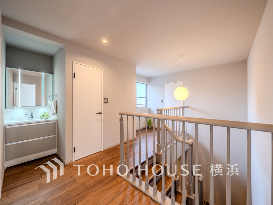 明るい光が差し込む開放的な階段ホール。清潔感のある洗面台と木目調の床が温かみを演出します。