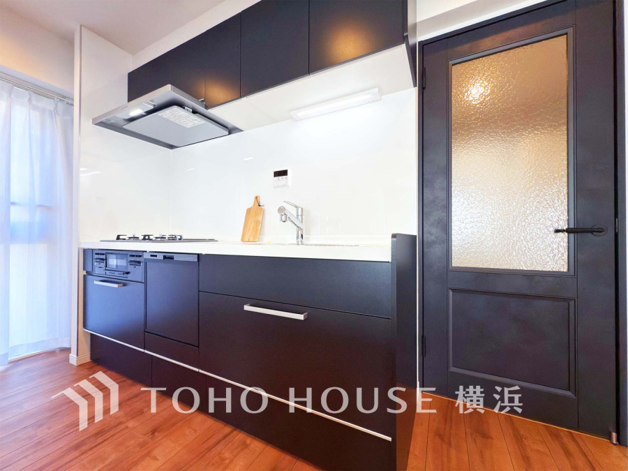 スタイリッシュなダークカラーのシステムキッチン。収納豊富で使い勝手が良く、明るい自然光が差し込みます。