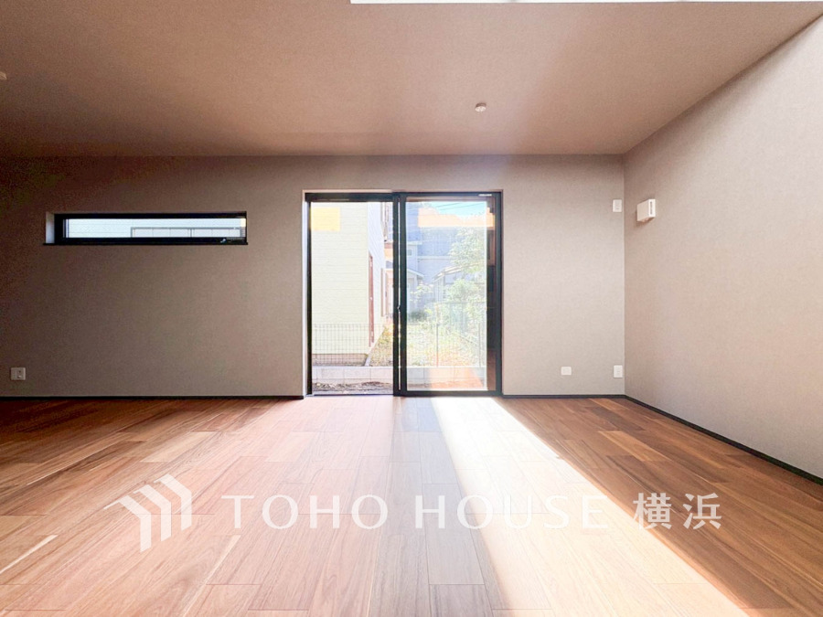 大きな窓から自然光が差し込む、温かみのある広々としたリビング空間。シンプルで落ち着いた内装が魅力です。