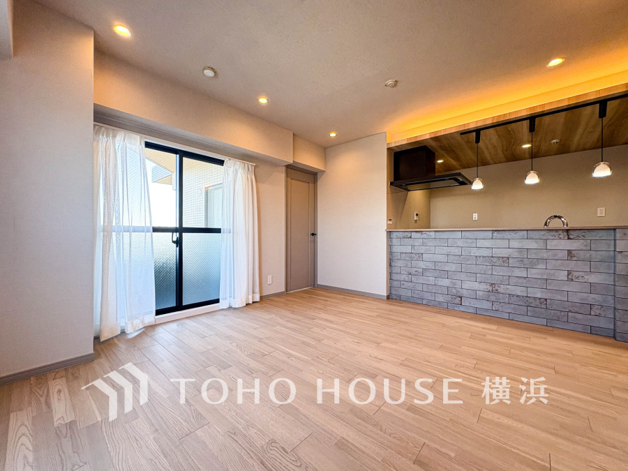 ナチュラルな木目床と間接照明が温かみを演出する、開放感あふれるリビングダイニング空間です。