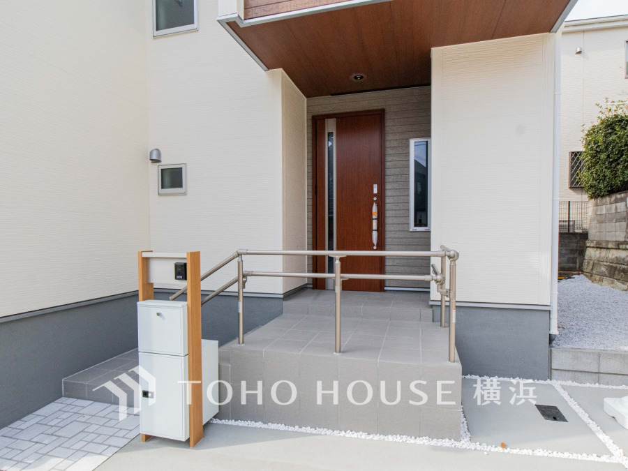 落ち着いた木目調ドアと手すり付きの玄関アプローチで、安心・快適な出入りを実現した住宅の入口です。