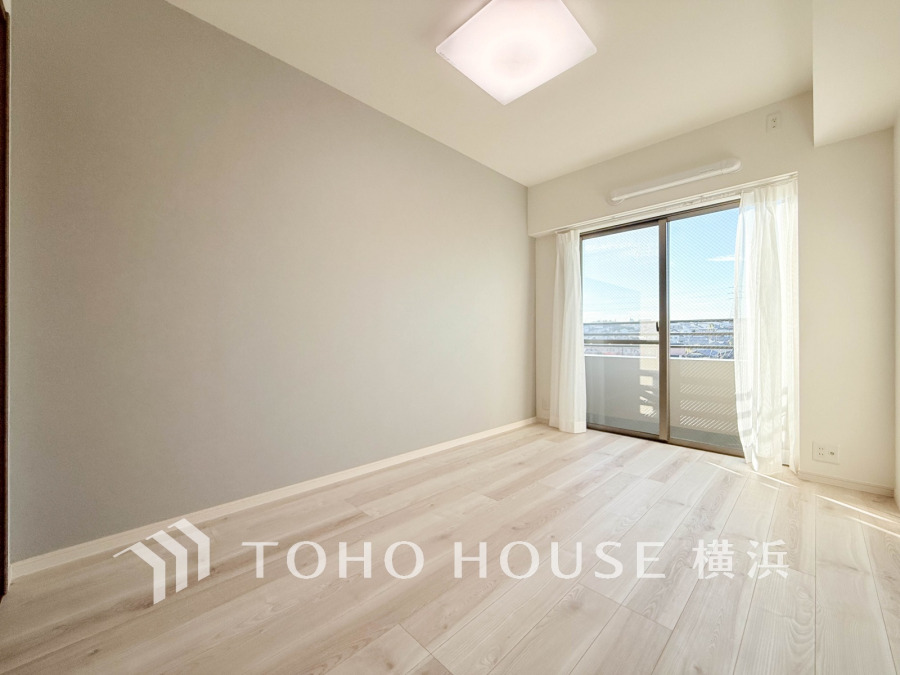 明るい陽光が差し込む、シンプルで清潔感あふれる洋室。バルコニーに面し開放感があります。