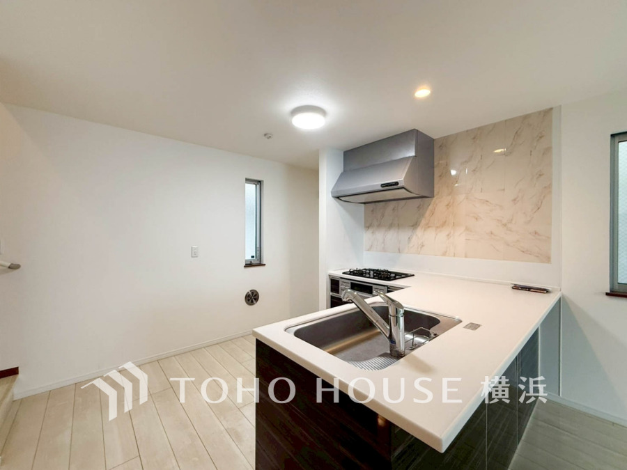 清潔感あふれる白を基調としたキッチン。対面式で家族との会話も楽しめる、使いやすい空間設計です。