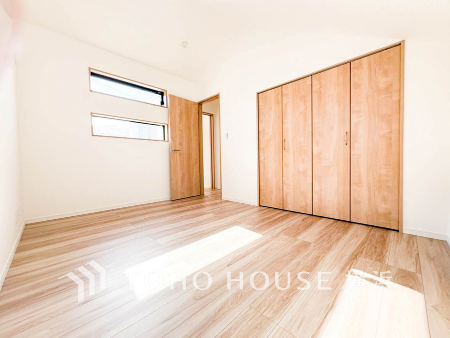 明るい光が差し込むナチュラルな木目調の床と収納が魅力の、シンプルで使いやすい洋室です。