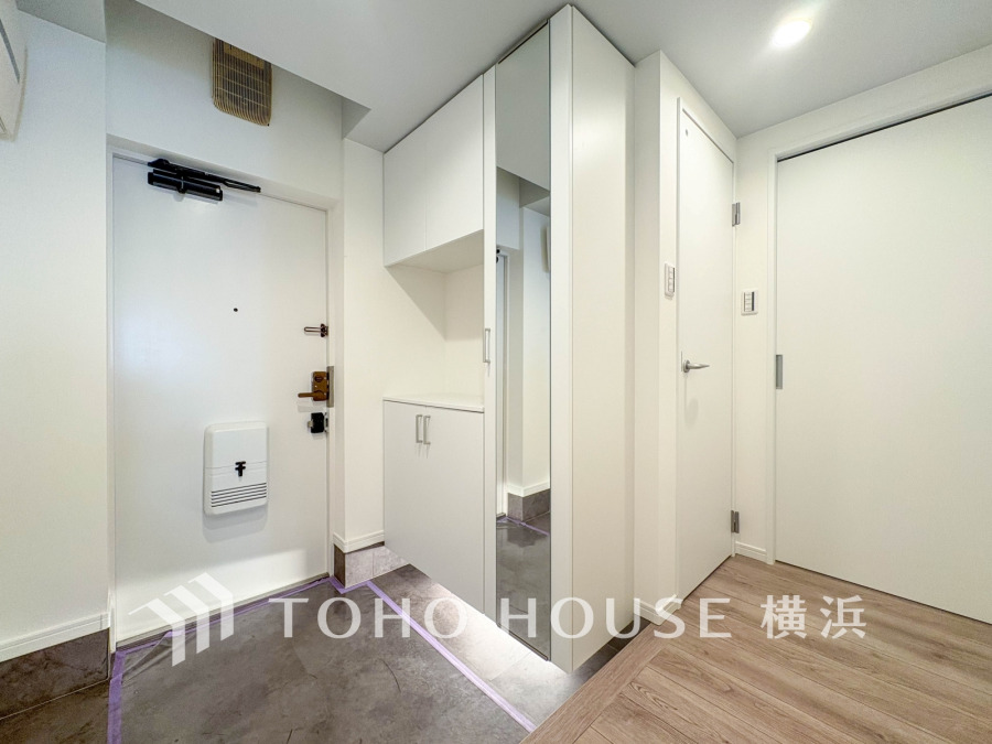 清潔感あふれるホワイトの玄関収納と姿見付きで、広々とした開放感のある玄関スペースです。