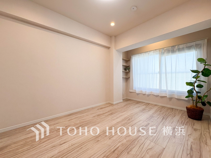 明るい窓辺とナチュラルな木目調フロアが調和した、シンプルで清潔感のある洋室です。