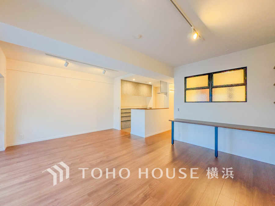 明るい自然光が差し込む広々としたリビング。スタイリッシュなキッチンと便利なカウンターデスク付き。