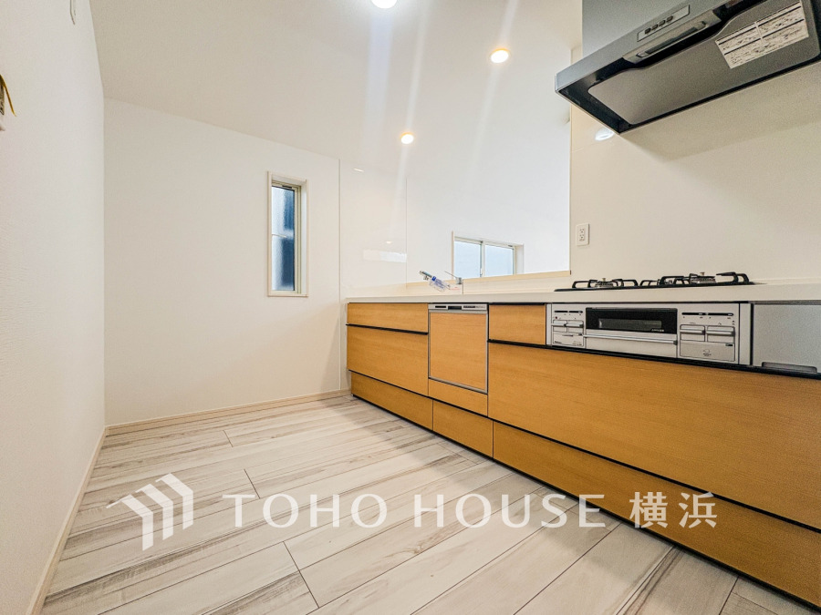 木目調の収納が映える、明るく開放的なシステムキッチン。機能性とデザイン性を兼ね備えた空間です。